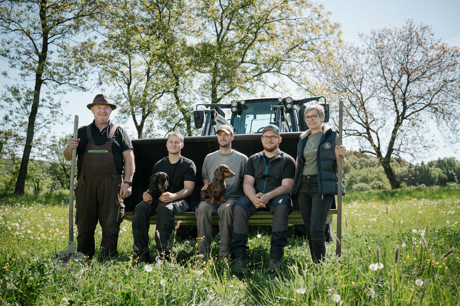 Familie Hofmann und Team mit Hunden vor einem Traktor am Wiesenthof